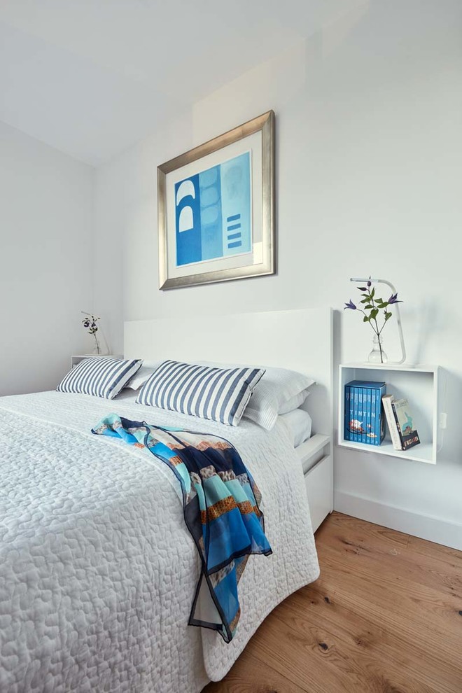 This is an example of a medium sized coastal master bedroom in Dublin with white walls and light hardwood flooring.