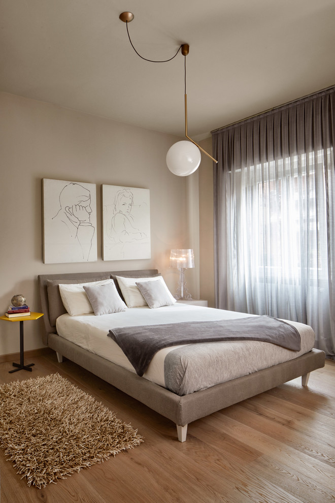 Contemporary guest and grey and brown bedroom in Other with beige walls, medium hardwood flooring and brown floors.