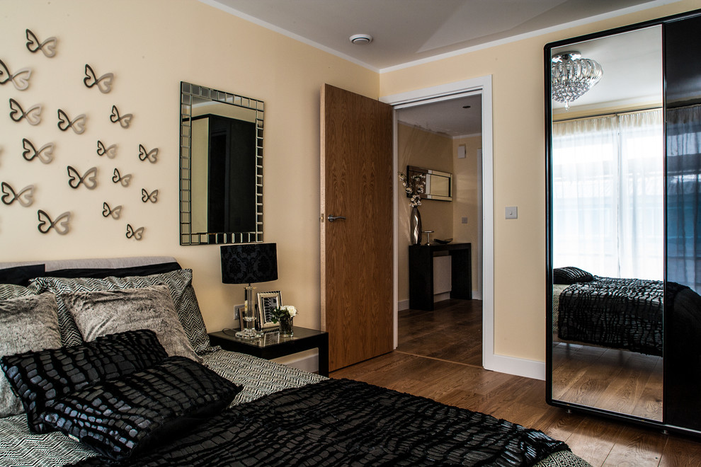 Imagen de dormitorio moderno de tamaño medio con paredes beige y suelo de madera clara
