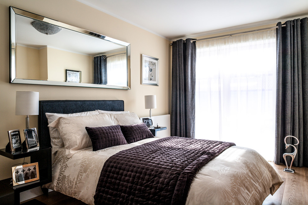 Foto de dormitorio moderno de tamaño medio con paredes beige y suelo de madera clara