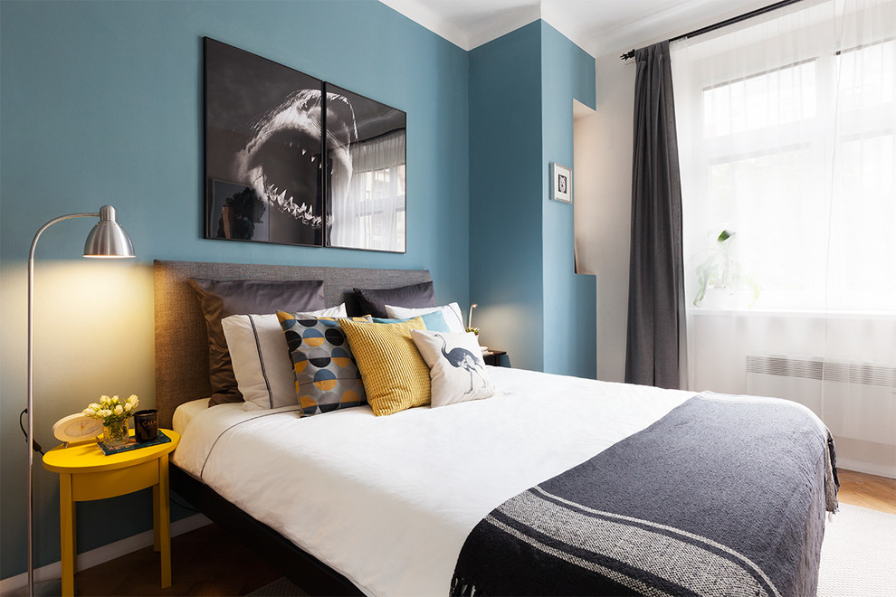 This is an example of a medium sized contemporary master and grey and silver bedroom in London with blue walls, light hardwood flooring and no fireplace.