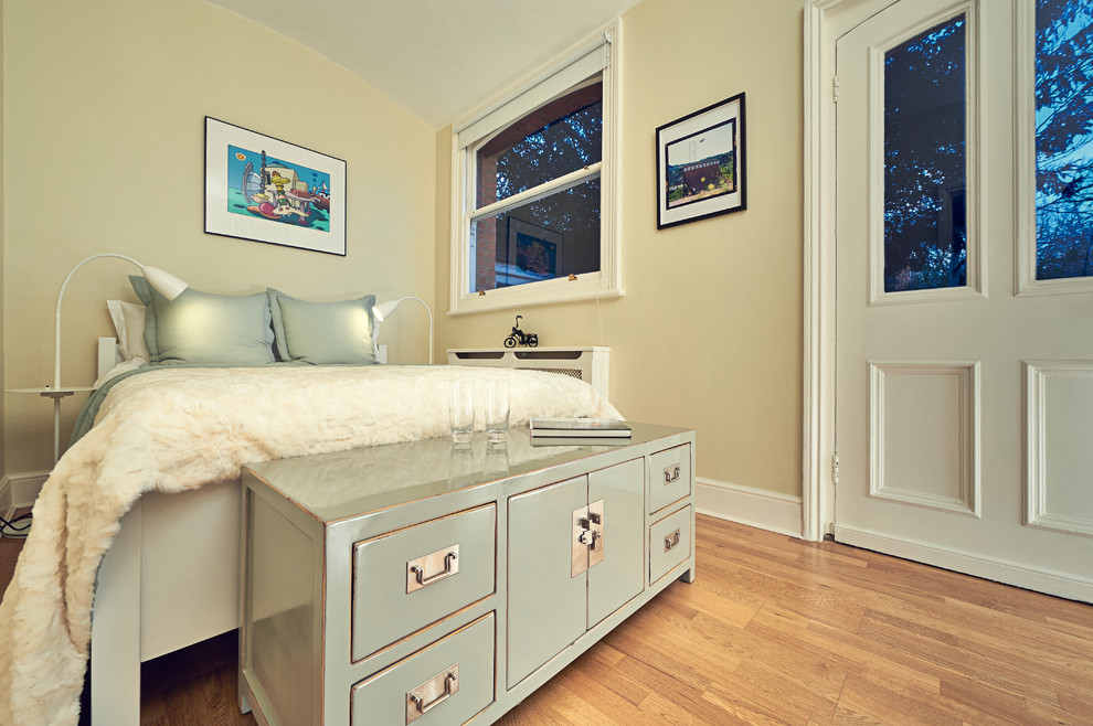 Cette image montre une petite chambre d'amis traditionnelle avec un mur beige et un sol en bois brun.