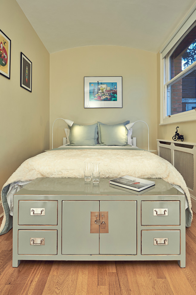 Example of a small transitional guest medium tone wood floor bedroom design in London with beige walls