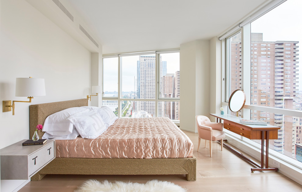 Modelo de dormitorio principal y beige y rosa actual sin chimenea con suelo de madera clara y paredes blancas