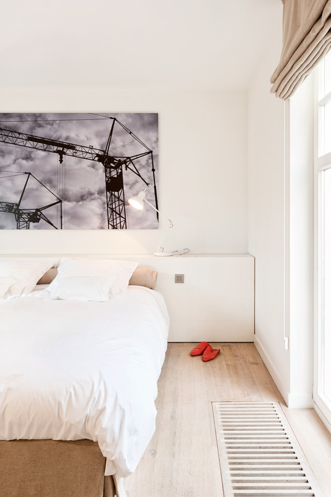 Bild på ett minimalistiskt sovrum, med vita väggar och ljust trägolv