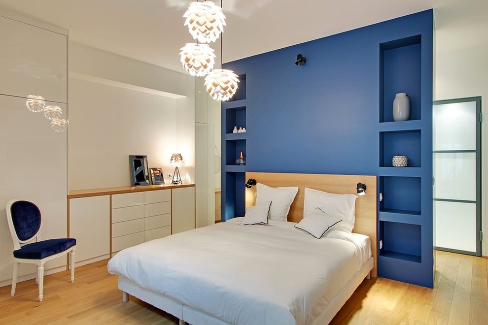 Ispirazione per una grande camera matrimoniale design con pareti blu, pavimento in legno massello medio e nessun camino