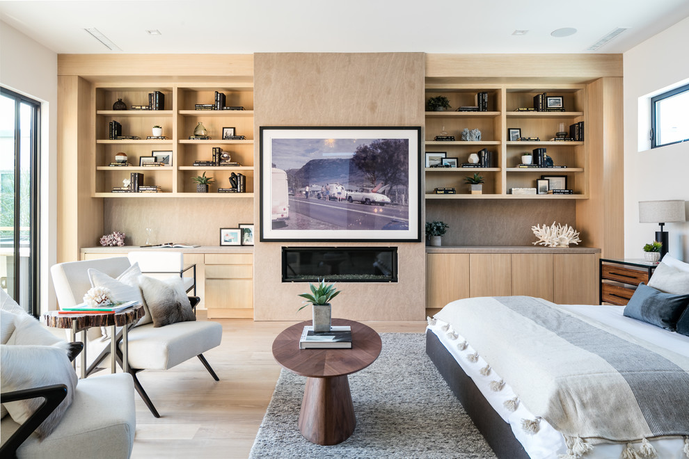 Modernes Hauptschlafzimmer mit weißer Wandfarbe, hellem Holzboden, Gaskamin und Kaminumrandung aus Stein in Los Angeles