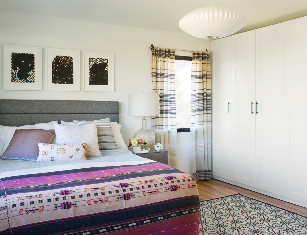 Esempio di una camera da letto minimalista con pareti beige e parquet chiaro