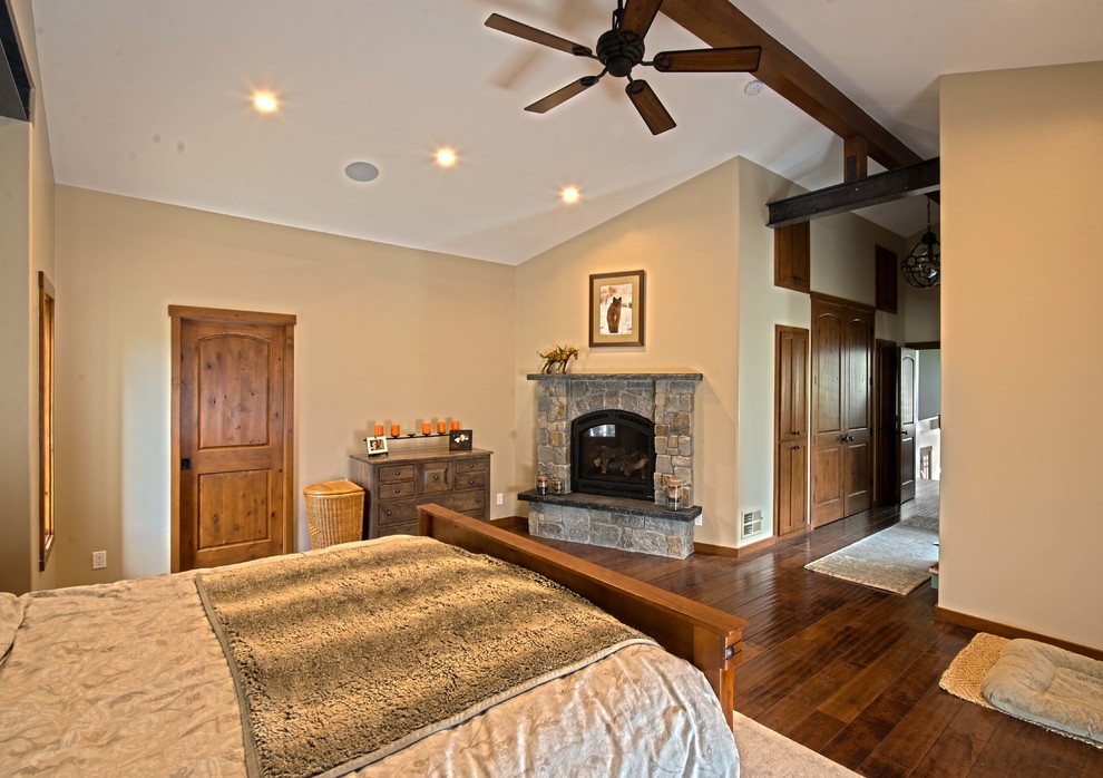 Inspiration for a large classic master bedroom in San Francisco with beige walls, dark hardwood flooring, a standard fireplace, a stone fireplace surround and brown floors.