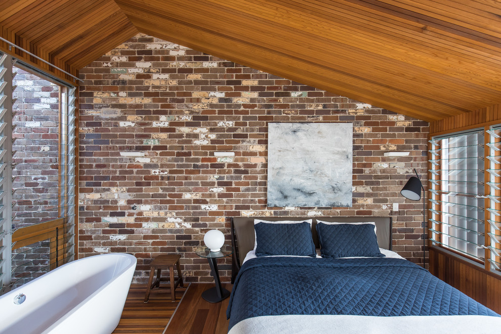 Großes Industrial Hauptschlafzimmer ohne Kamin mit braunem Holzboden in Sydney