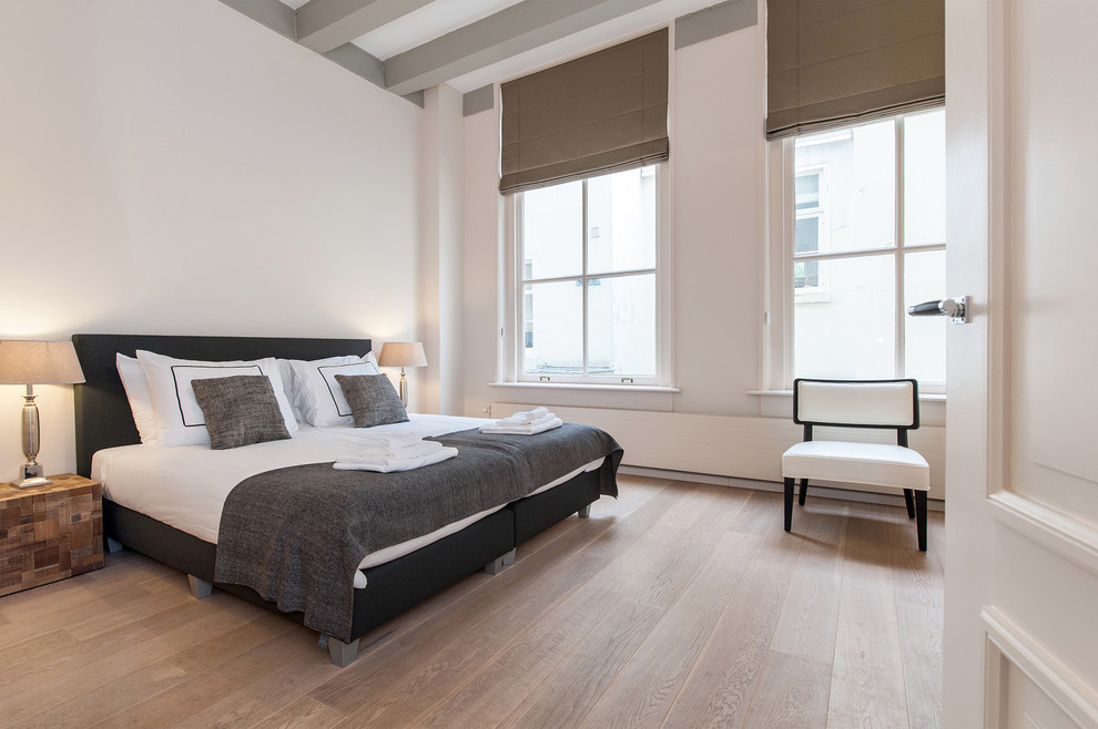 Großes Modernes Hauptschlafzimmer ohne Kamin mit weißer Wandfarbe und braunem Holzboden in Amsterdam