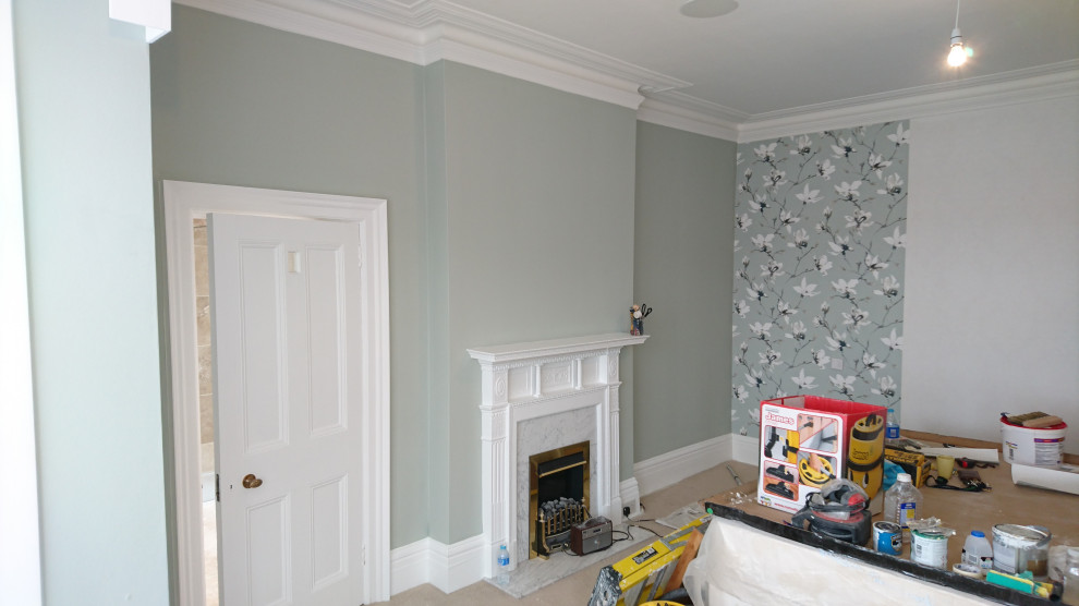 Réalisation d'une chambre tradition avec un mur gris, un manteau de cheminée en métal et du papier peint.
