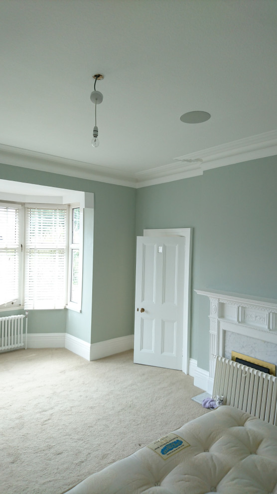 Klassisches Schlafzimmer mit grauer Wandfarbe, Kaminumrandung aus Metall und Tapetenwänden in Sussex
