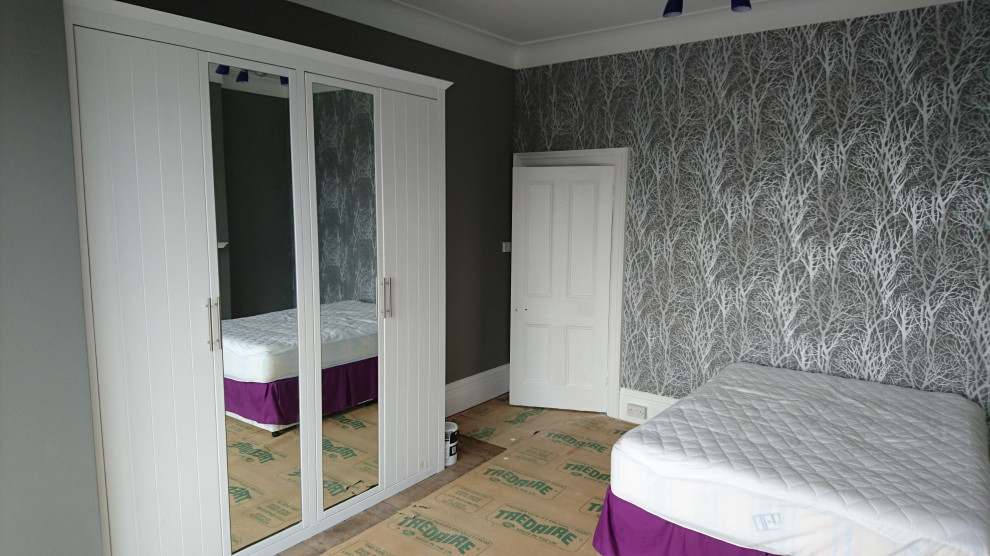 Aménagement d'une chambre classique avec un mur gris, un manteau de cheminée en métal et du papier peint.