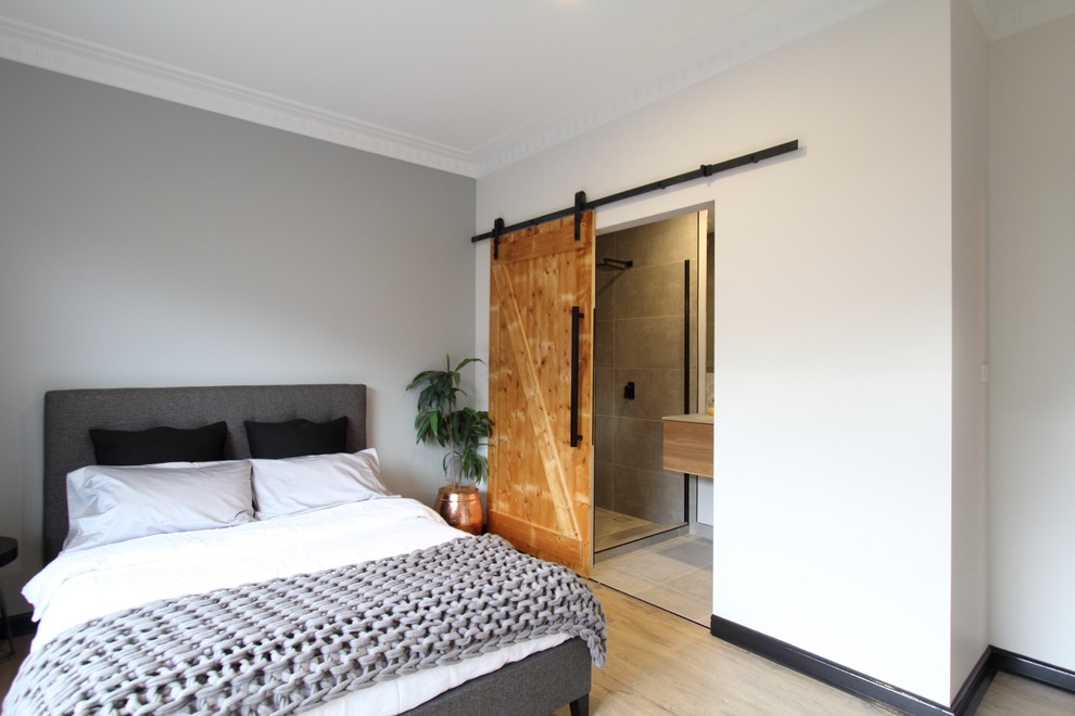 Foto de dormitorio principal industrial de tamaño medio con paredes grises y suelo laminado