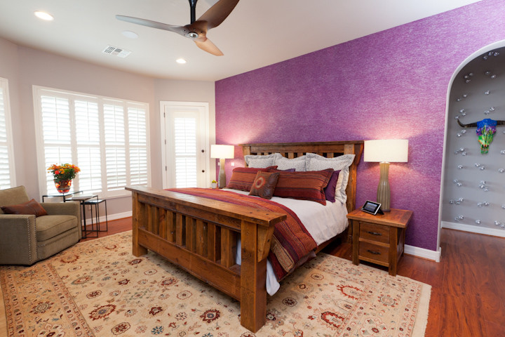 Foto de dormitorio principal rural grande sin chimenea con paredes púrpuras, suelo de madera en tonos medios y suelo marrón