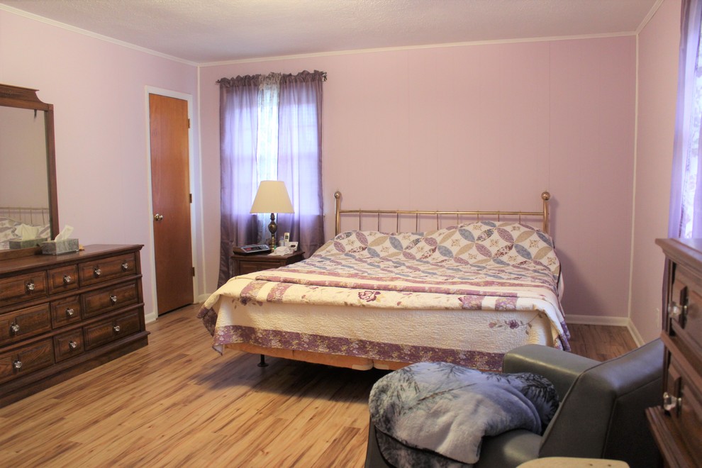 Modelo de dormitorio principal tradicional grande con paredes púrpuras y suelo vinílico