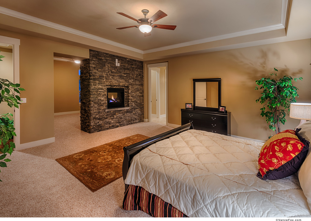 Inspiration for a traditional master bedroom in Other with brown walls, carpet, a two-sided fireplace and a stone fireplace surround.