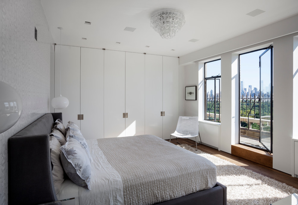 Inspiration pour une chambre design de taille moyenne avec un mur blanc et un sol en bois brun.