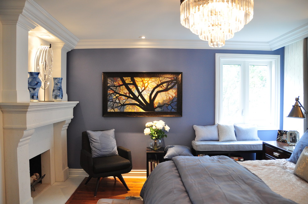 Foto di una camera matrimoniale chic di medie dimensioni con pareti blu, pavimento in legno massello medio, camino classico e cornice del camino in pietra