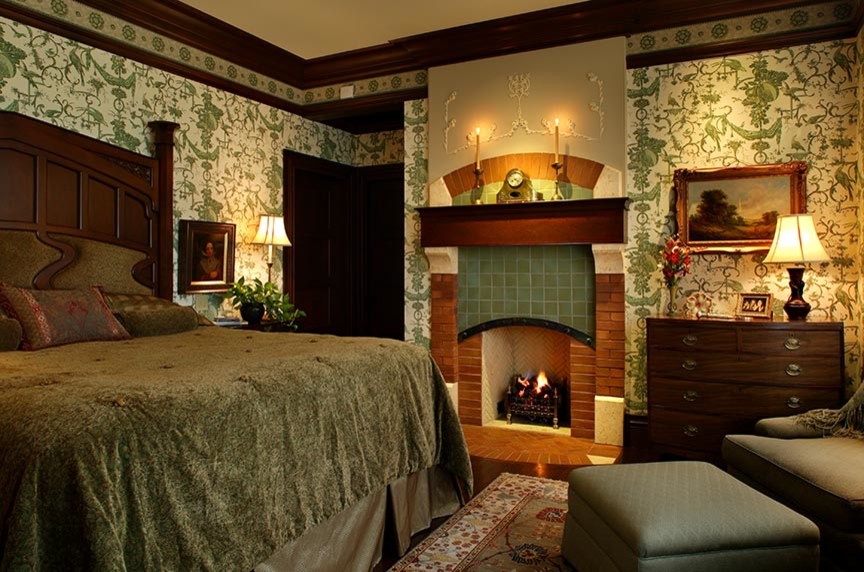 На фото: хозяйская спальня среднего размера в стиле кантри с зелеными стенами, темным паркетным полом, стандартным камином и фасадом камина из плитки с