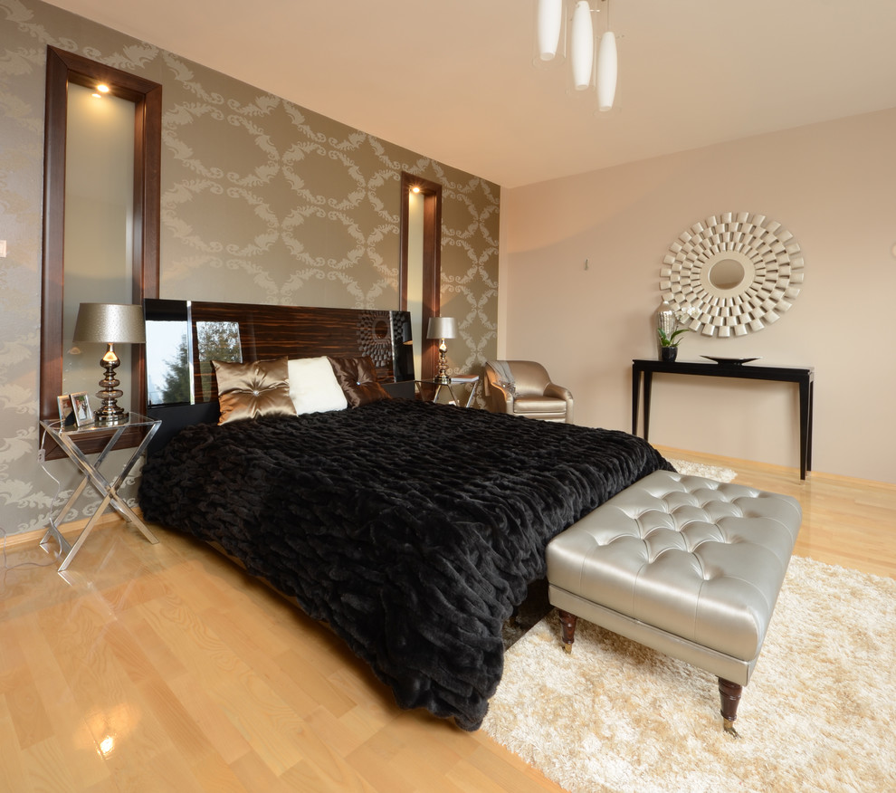 Immagine di una camera da letto design con pareti grigie e parquet chiaro