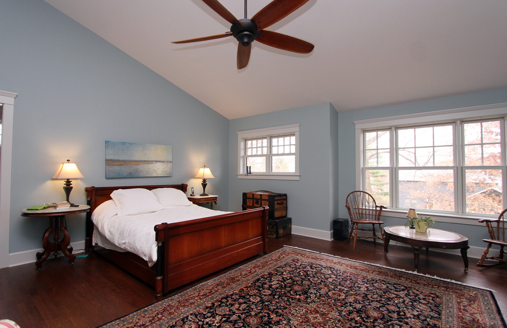 Immagine di una camera matrimoniale stile americano di medie dimensioni con pareti blu, pavimento in legno massello medio e nessun camino