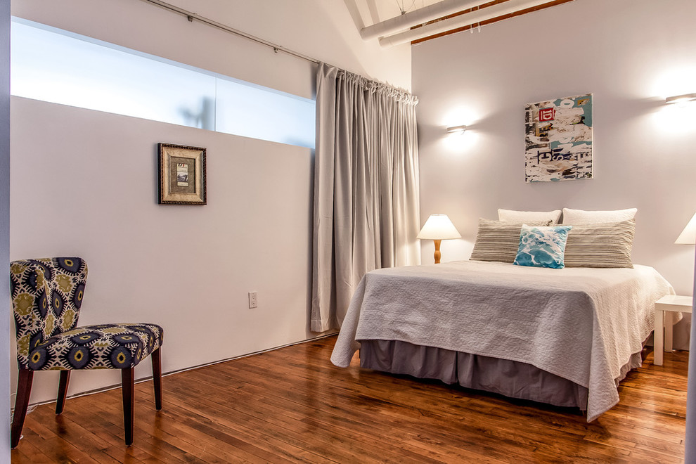 Diseño de habitación de invitados urbana de tamaño medio con paredes grises y suelo de madera en tonos medios