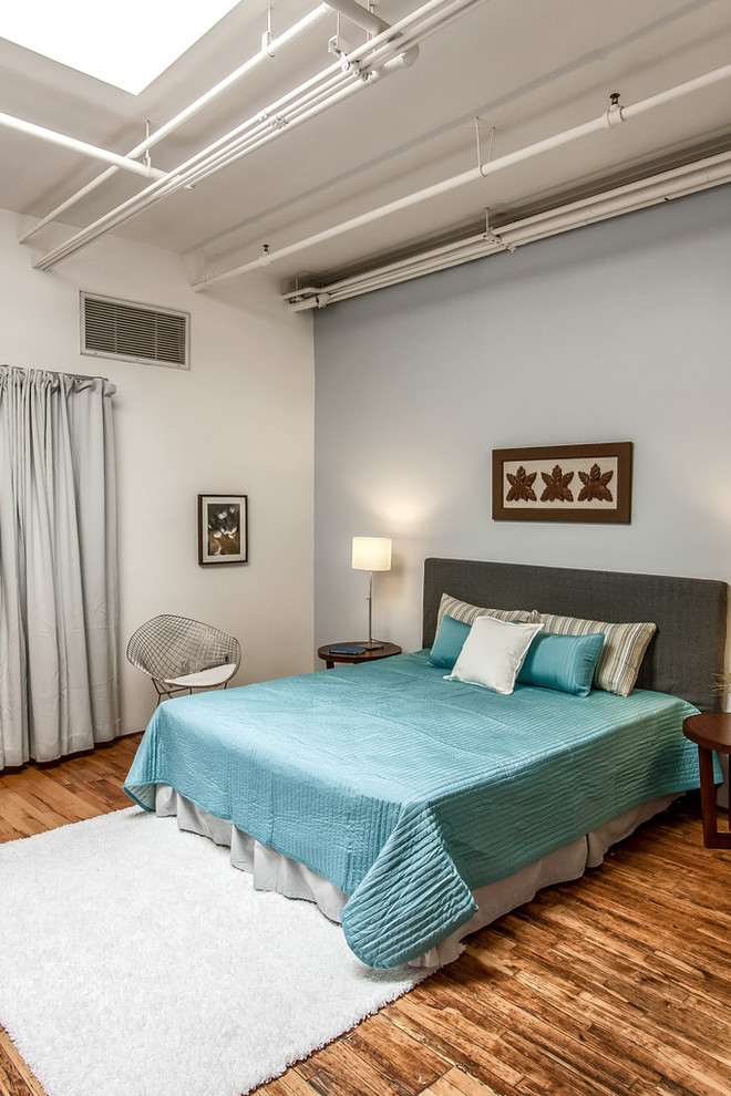 Großes Industrial Schlafzimmer ohne Kamin mit grauer Wandfarbe und braunem Holzboden in Los Angeles