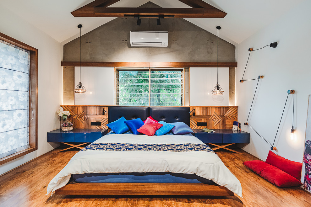 Asiatisches Schlafzimmer mit weißer Wandfarbe, braunem Holzboden und braunem Boden in Ahmedabad