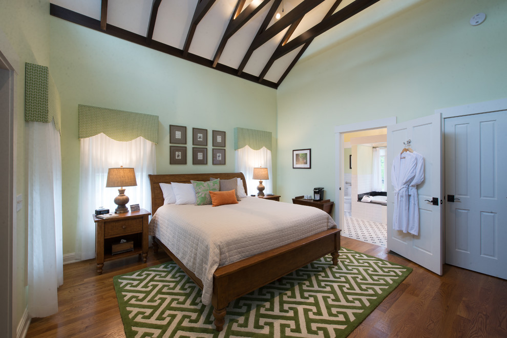 Aménagement d'une grande chambre parentale classique avec un sol en bois brun, une cheminée standard, un manteau de cheminée en plâtre, un sol marron et un mur vert.