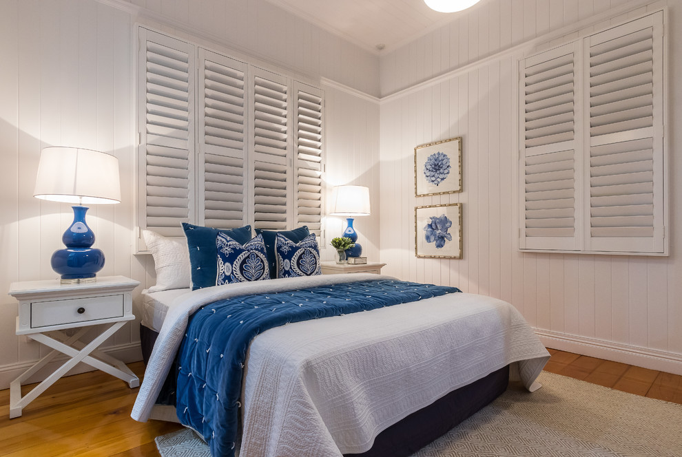 Foto di una camera da letto stile marinaro con pareti bianche, pavimento in legno massello medio e pavimento marrone