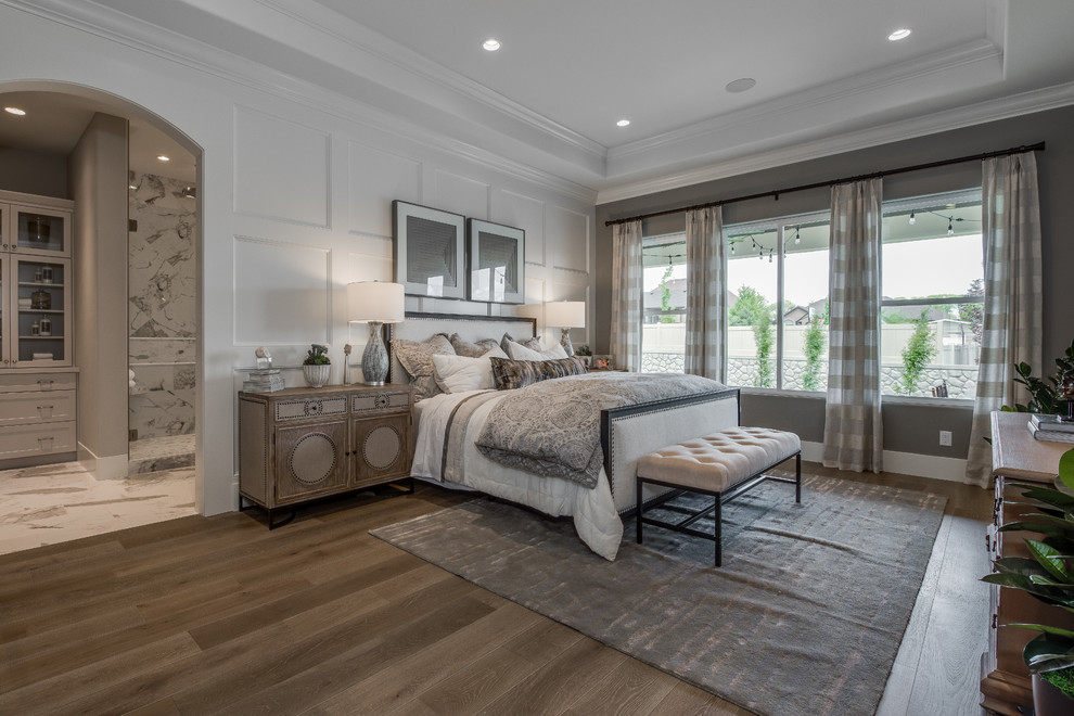 Ejemplo de dormitorio principal clásico grande sin chimenea con paredes grises, suelo de madera clara y suelo marrón
