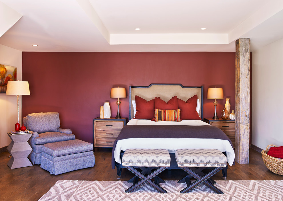Uriges Hauptschlafzimmer mit roter Wandfarbe und braunem Holzboden in Houston