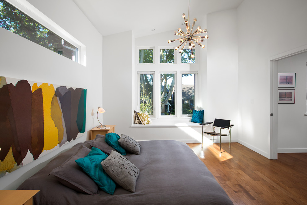 Diseño de dormitorio moderno de tamaño medio con paredes blancas y suelo de madera en tonos medios
