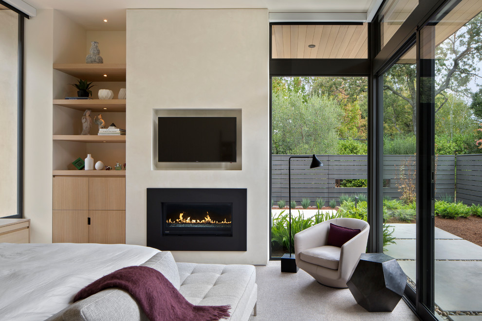This is an example of a contemporary master bedroom in San Francisco with beige walls, carpet and a ribbon fireplace.