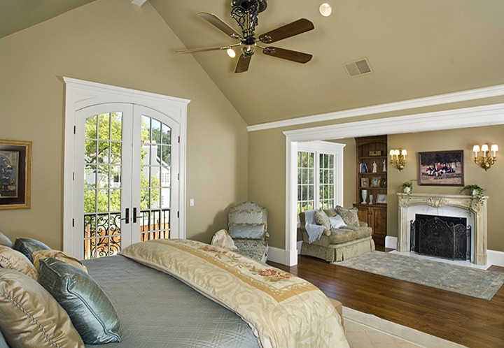 Aménagement d'une grande chambre parentale classique avec un mur beige, un sol en bois brun et un manteau de cheminée en pierre.