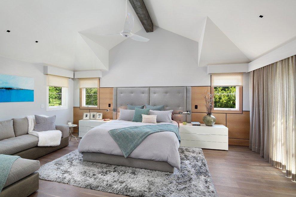Diseño de dormitorio principal tradicional renovado grande sin chimenea con paredes blancas, suelo de madera en tonos medios y suelo marrón