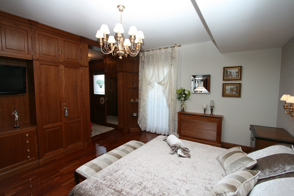 Foto de dormitorio principal tradicional renovado grande sin chimenea con paredes blancas y suelo de madera oscura