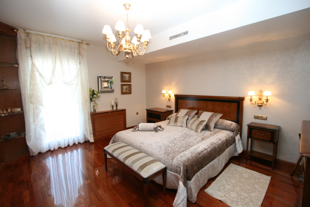 Diseño de dormitorio principal tradicional renovado grande sin chimenea con paredes blancas y suelo de madera oscura