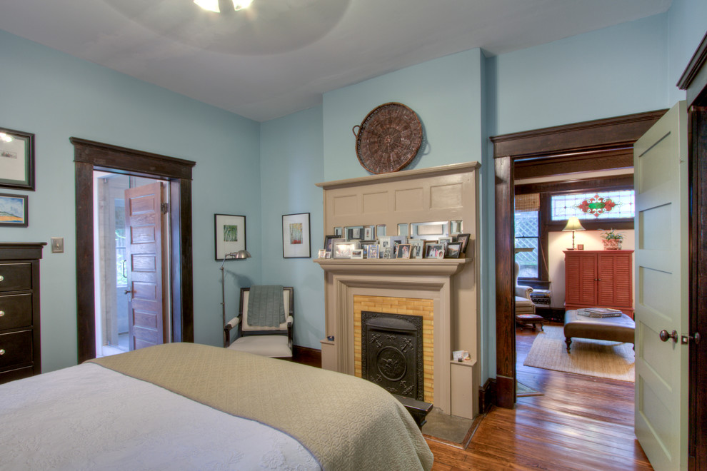 Arts and crafts medium tone wood floor bedroom photo in Atlanta with blue walls, a standard fireplace and a tile fireplace