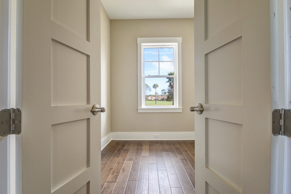 Diseño de habitación de invitados costera de tamaño medio sin chimenea con paredes beige, suelo de madera en tonos medios y suelo marrón