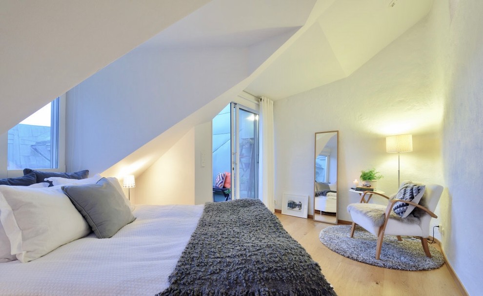 This is an example of a scandi master bedroom in San Francisco with white walls, light hardwood flooring and beige floors.