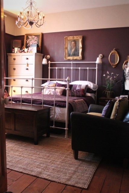 Großes Shabby-Look Hauptschlafzimmer mit lila Wandfarbe, dunklem Holzboden, Kamin und Kaminumrandung aus Metall in Wiltshire