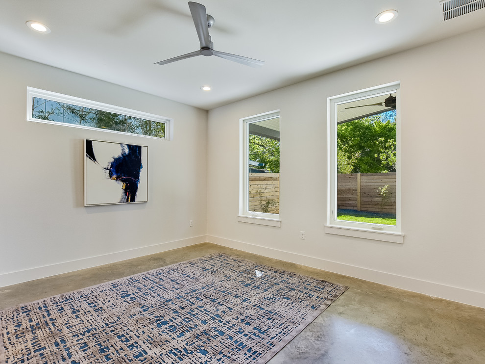 Mittelgroßes Mid-Century Gästezimmer ohne Kamin mit weißer Wandfarbe, Betonboden und beigem Boden in Austin
