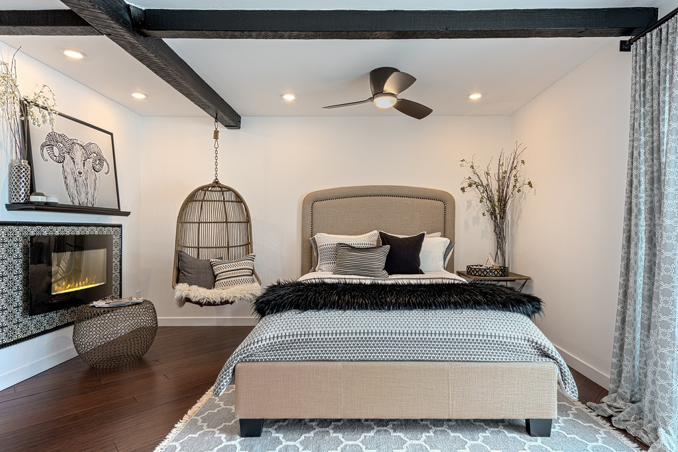 На фото: хозяйская спальня в стиле неоклассика (современная классика) с белыми стенами, темным паркетным полом, стандартным камином и фасадом камина из плитки с