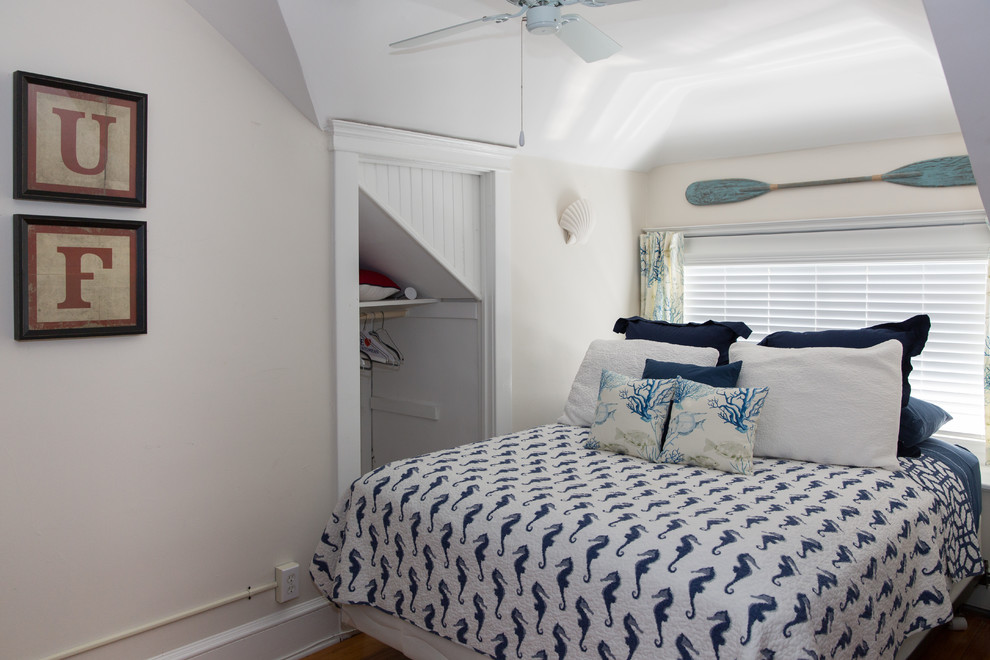 Foto de habitación de invitados costera de tamaño medio sin chimenea con paredes blancas y suelo de madera clara