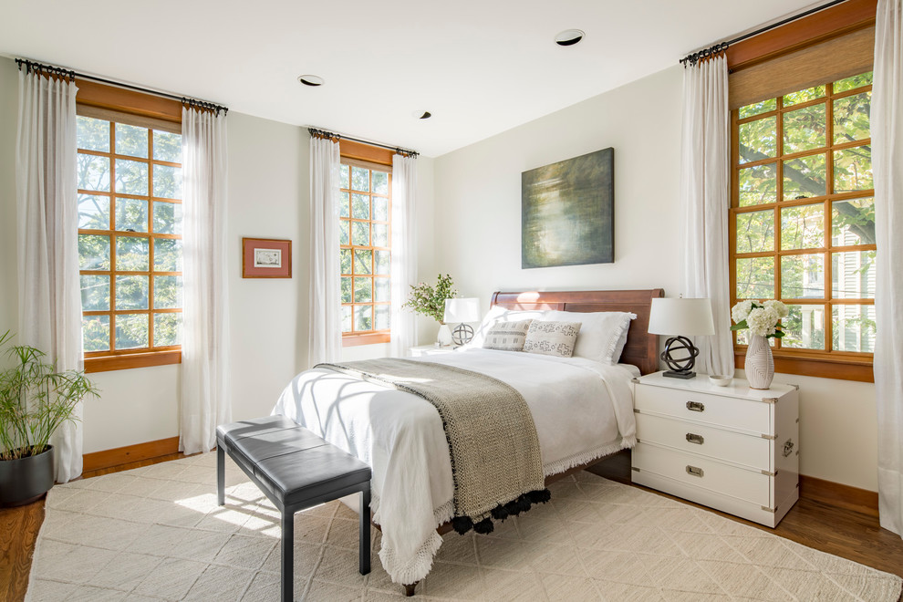Ejemplo de dormitorio principal tradicional renovado de tamaño medio sin chimenea con paredes blancas, suelo de madera en tonos medios y suelo marrón