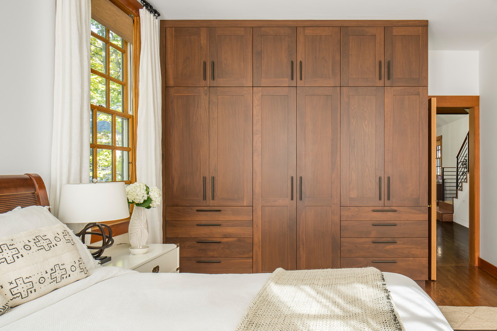 Imagen de dormitorio principal tradicional renovado de tamaño medio sin chimenea con paredes blancas, suelo de madera en tonos medios y suelo marrón