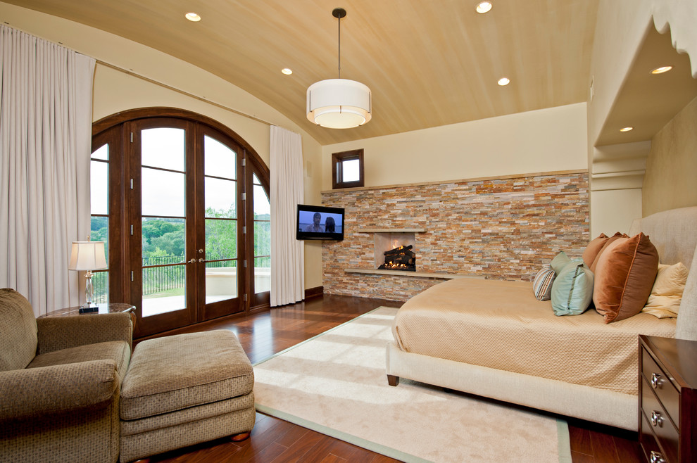 Klassisches Schlafzimmer mit beiger Wandfarbe, dunklem Holzboden, Kamin und Kaminumrandung aus Stein in Austin